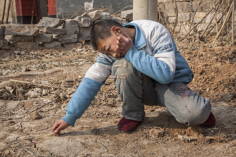 2011年2月2日，除夕，刘英超持香捂着耳朵放鞭炮，他想要看看夹在地缝里的鞭炮可以炸出多大的洞。作者：刘磊